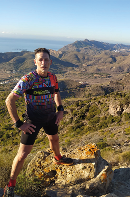 A man wearing a colorful shirt stands on a rocky hillside, posing for a picture. AI generated content
