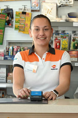A woman is smiling and holding a card reader at a counter. AI generated content