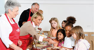 A group of people are gathered around a table with food. Description generated by AI